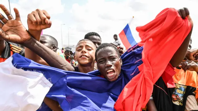 Manifestation de partisans des chefs militaires du Niger devant une base aérienne nigérienne, avec un drapeau russe visible