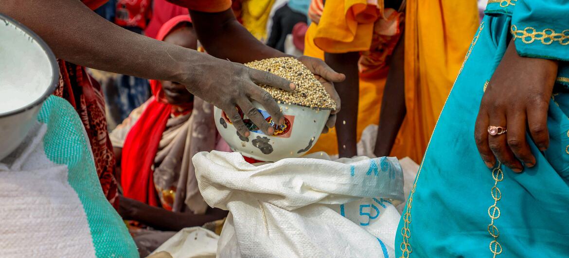 Distribution d’aide alimentaire à Adré, Tchad : un membre du PAM verse du sorgho pour des réfugiés soudanais