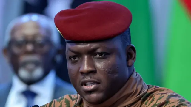 On voit Ibrahim Traoré en gros plan, vêtu d'une tenue militaire beige et d'un béret rouge.